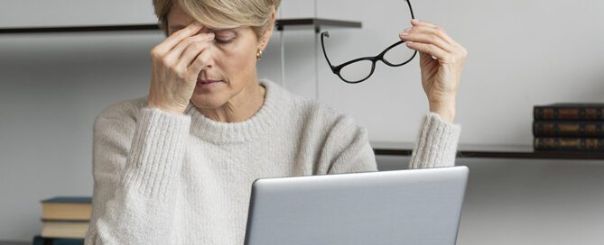 "Woman with headache because of her glasses. At her laptop"